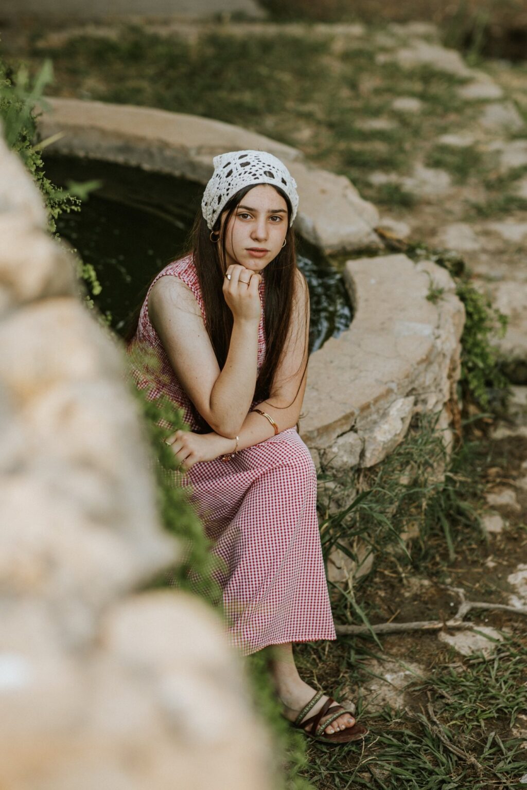 נערה במטפחת סרוגה ליד באר אבן